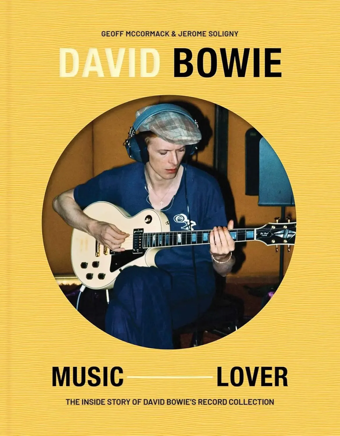 Cover of the book David Bowie: Music Lover featuring David Bowie wearing headphones and a cap, playing an electric guitar in a recording studio. The cover is yellow with black text.
